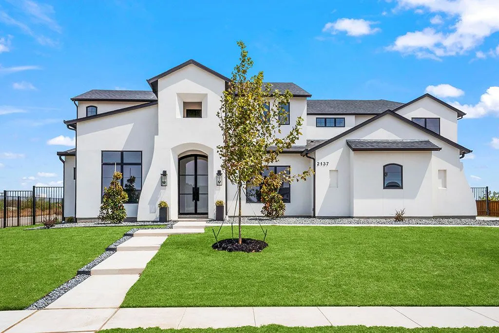 Modern white house with green lawn.
